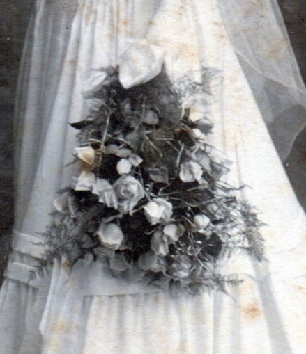 Bridal bouquet of long stemmed white roses held together with a white satin bow.