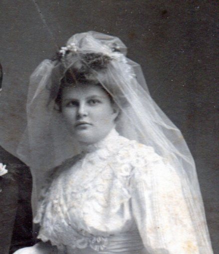 Close up of bride with upswept hair with a veil attached on top and the lace ruffles on the bodice.