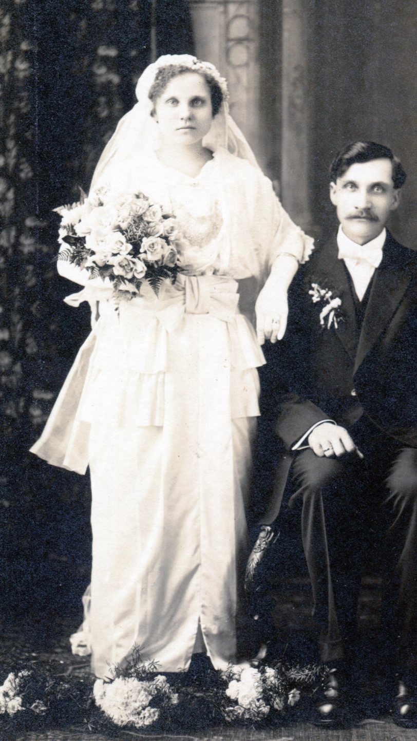 Bride in white flowing V-neck dress with wide band and bow at waist front.