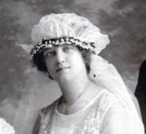 Brides headdress of a net circle gathered around the edges to form a poof and edged with greenery with veil attached at back.