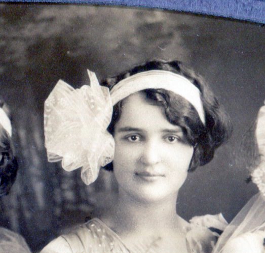 Bridesmaid's headdress of wide white band around her head with large net puff on the right side of her head.