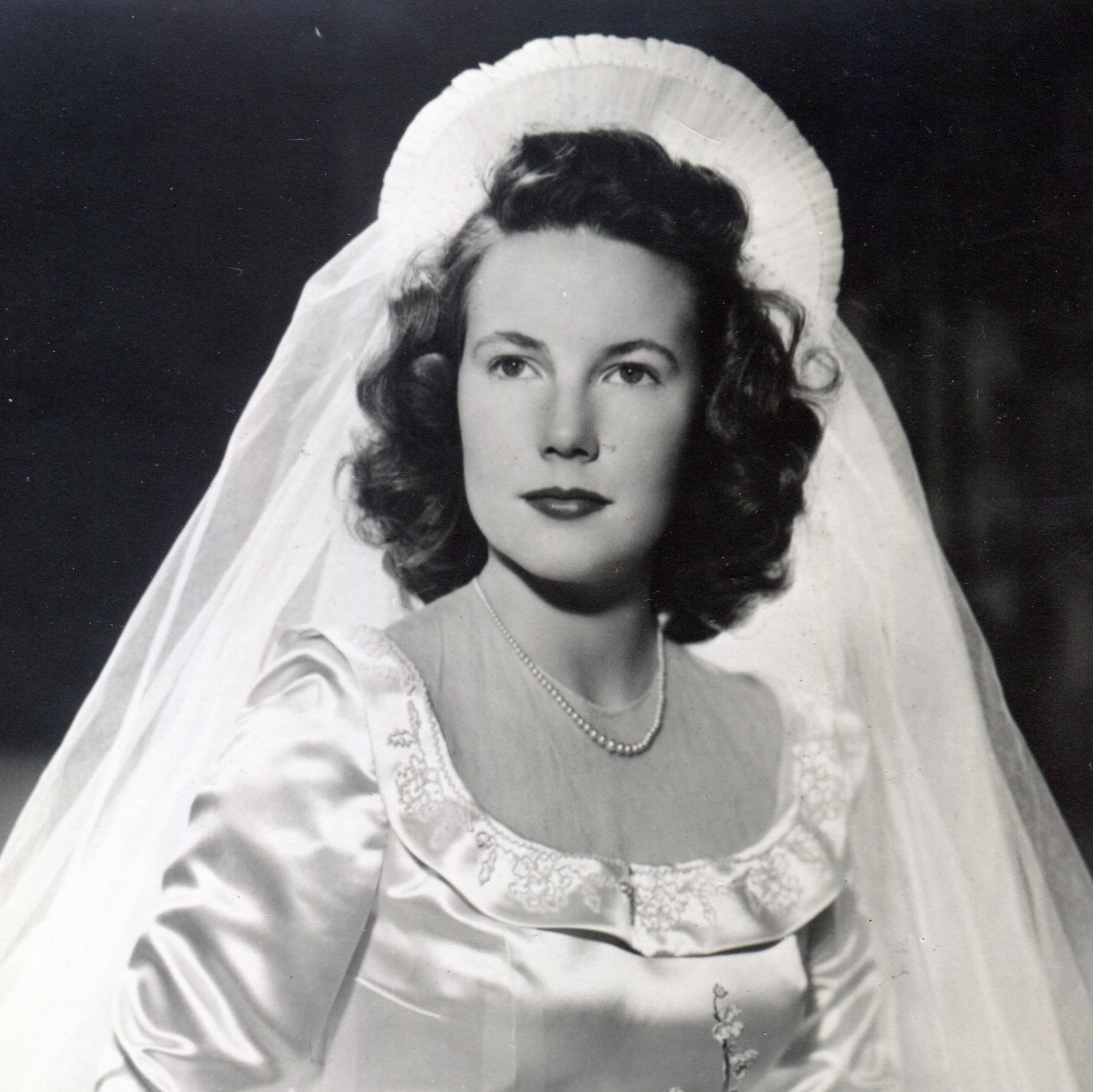 Bride in pleated net ruffle headpiece that sticks up above her face with a shoulder length veil attached at back
