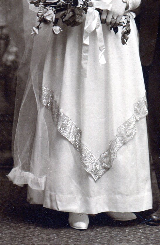 Bride's skirt showing overlapping layer that comes to a point with fancy band on edge