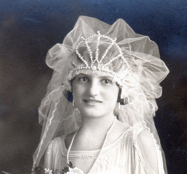 The bridal headpiece in a fantasy "Egyptian" style with pearls on wire creating a crown and net puff behind