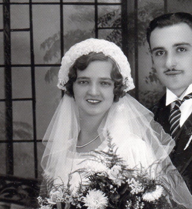 Bodice of bridal gown showing scooped neckline and decorated headpiece with veil