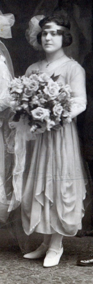 Brides maid with flowing chiffon dress with layers of draping on skirt and large bouquet of roses.