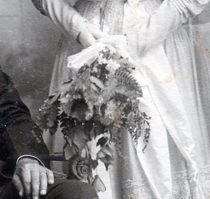 Bridal bouquet of two large dark colored orchids, smaller flowers and greenery.