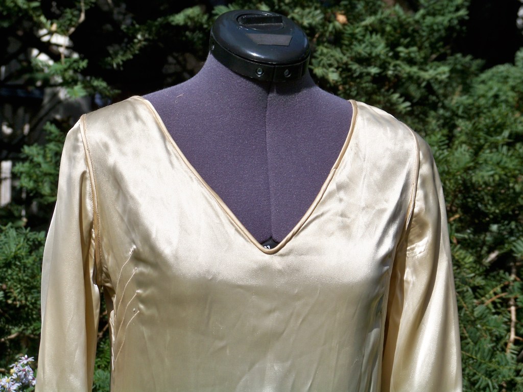 Close up of cream satin wedding gown with deep V neckline front.