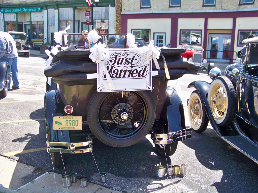Model A Ford convertible with Just Married sign on back and tin cans tied to the bumper.