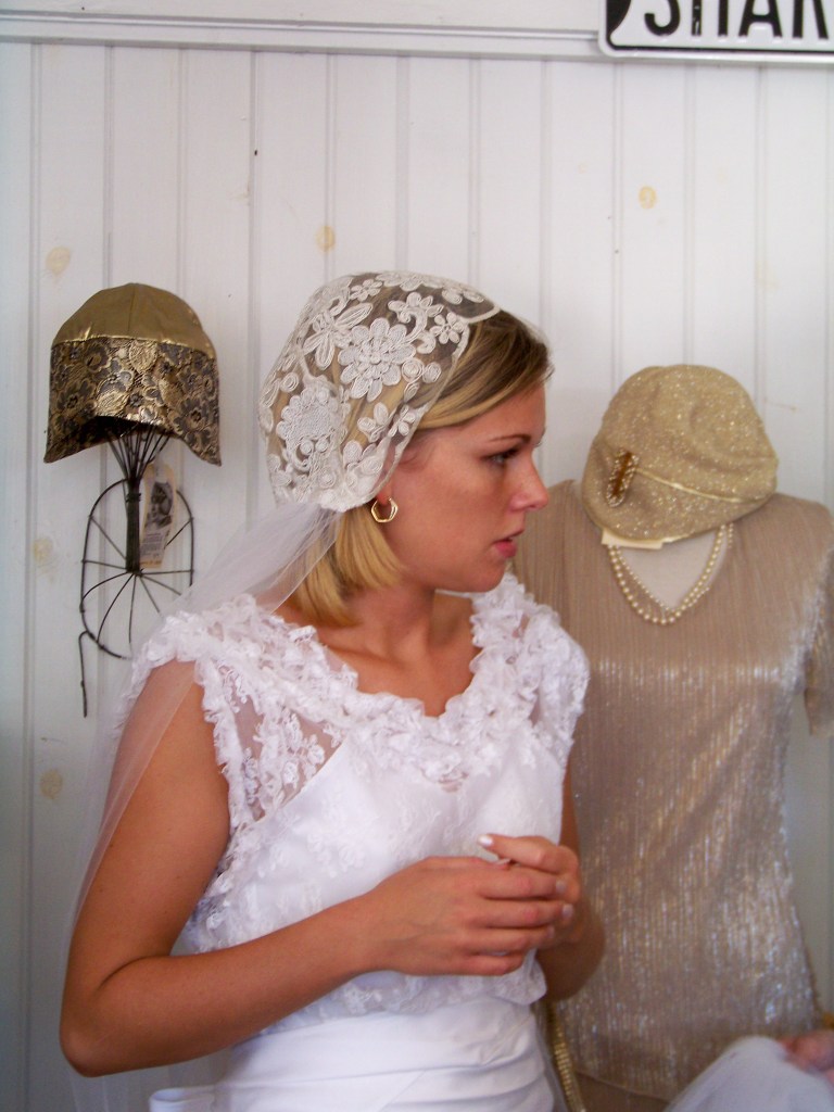 Bridal cap of large flowers embroidered on sheer net with net veil attached at back.