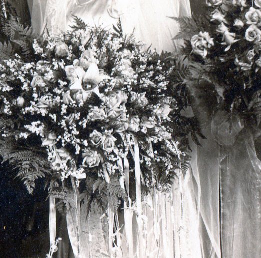 Large bridal bouquet of Star Lily in middle with roses, small flowers and fern fronds with waterfall of ribbons hanging down with small flower buds tied on.