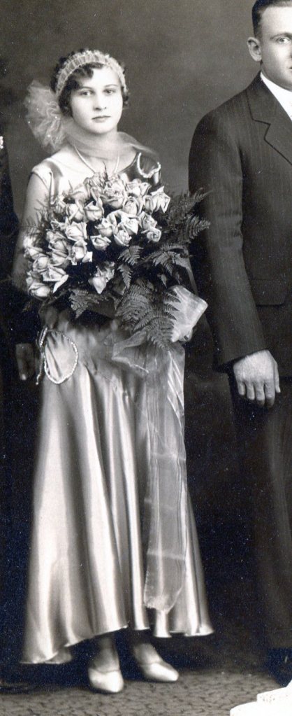 Bridesmaid in long shiny satin sleeveless dress and holding a large bouquet of roses.