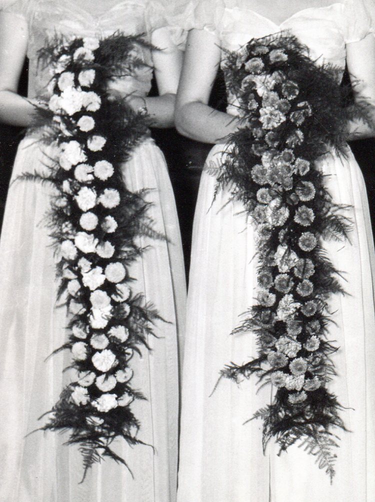 Close up showing Bridesmaids' unusual bouquets of long band of flowers and greenery hanging down almost to the floor. 